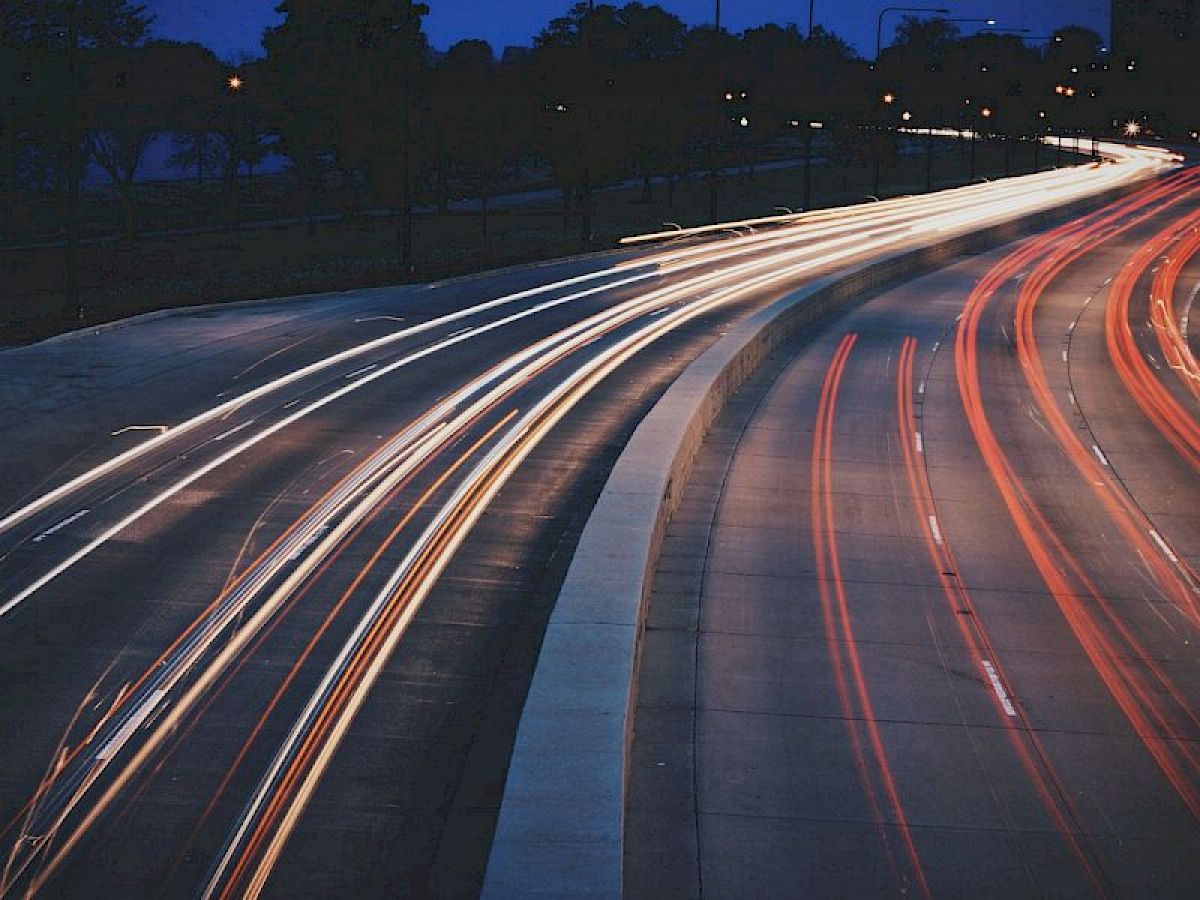 The image shows a long exposure shot of a busy highway at night with light trails from vehicles creating streaks of light on the road.